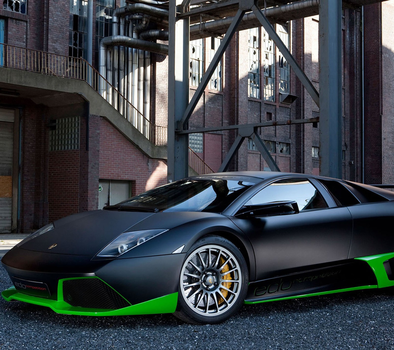 A close up of a black and green sports car parked in front of a building (black, car, green)