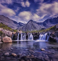 Majestätische Wasserfälle, die von rauen Bergen unter einem bewölkten Himmel herabfallen