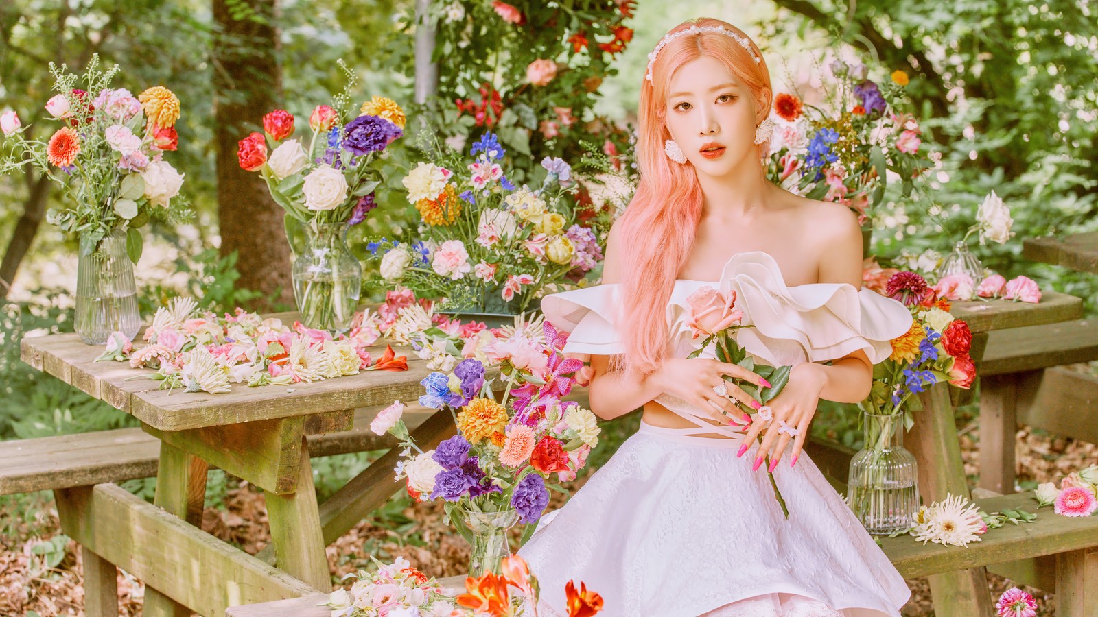 Une femme aux cheveux roses assise sur un banc devant des fleurs (kim lip, kim rip, 김립, kim jong un, kim jung eun)