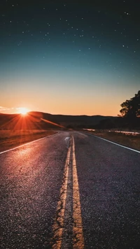 Pôr do sol sobre estrada asfaltada em uma paisagem natural