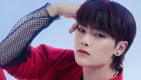 Yang Jeong In de Stray Kids adoptant une pose frappante dans une tenue rouge vibrante, dégageant confiance et charisme.