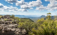 Paysage montagneux majestueux avec une végétation luxuriante et des nuages dramatiques au-dessus.