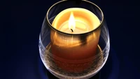 Elegant candle in a glass holder, casting a warm glow.