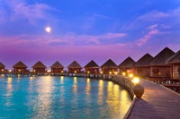 Sérénité du crépuscule dans un resort aux Maldives : Villas sur pilotis reflétant les eaux éclairées par la lune