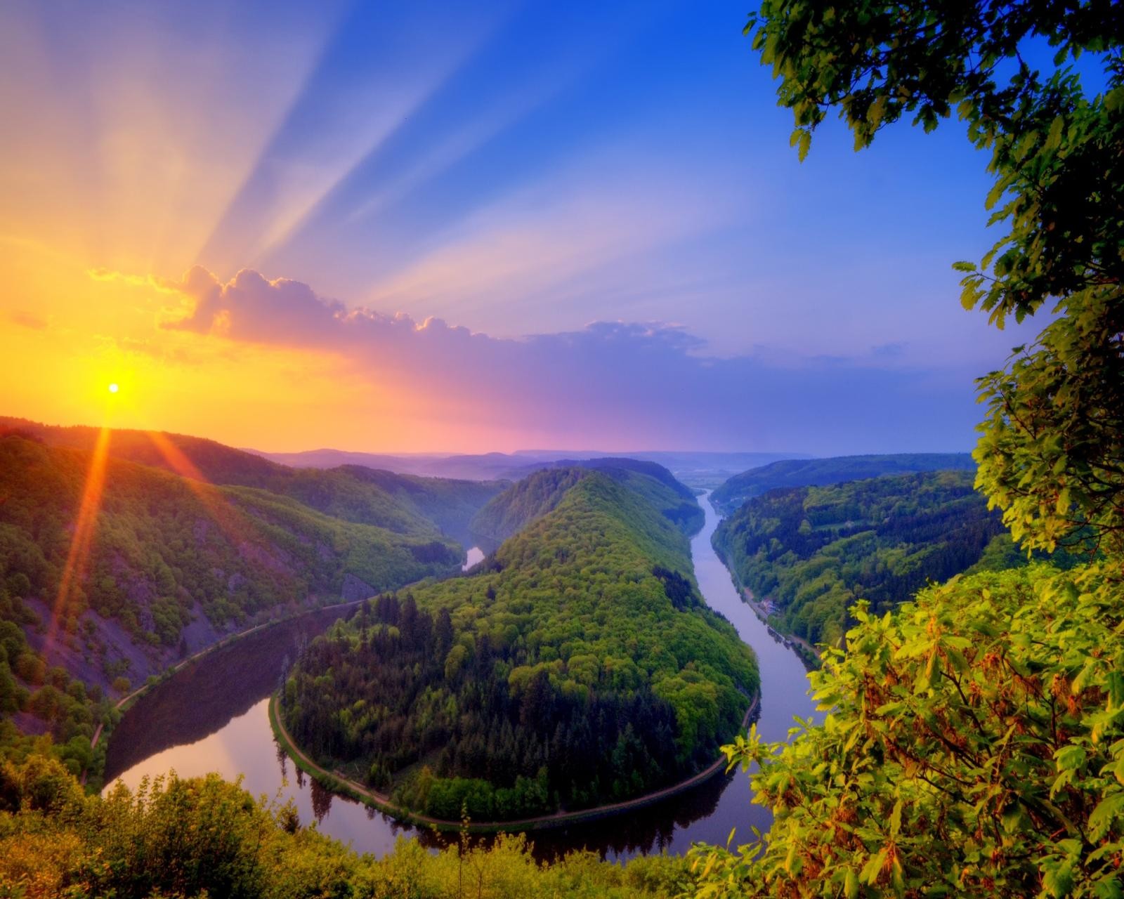 A view of a river running through a lush green valley (lake, sunshine)