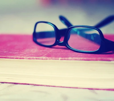 Lunettes reposant sur un livre rose