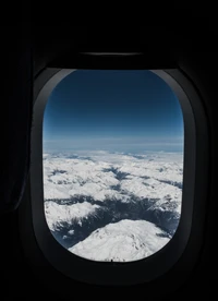 Montanhas cobertas de neve sob um céu azul claro vistas da janela de um avião