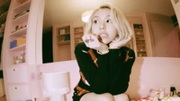 Chaeyoung von TWICE posiert verspielt in einem gemütlichen, pastellfarbenen Raum und zeigt ihren einzigartigen Stil und Charme.