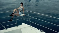 Yujin d'IVE pose avec style sur un yacht, incarnant une ambiance estivale chic contre un fond océanique serein.