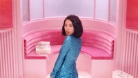 Chaeyoung con un brillante atuendo azul, posando en un vibrante entorno rosa.