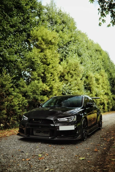 Mitsubishi Lancer Evolution parked on a tree-lined gravel path, showcasing its sleek design and sporty modifications.