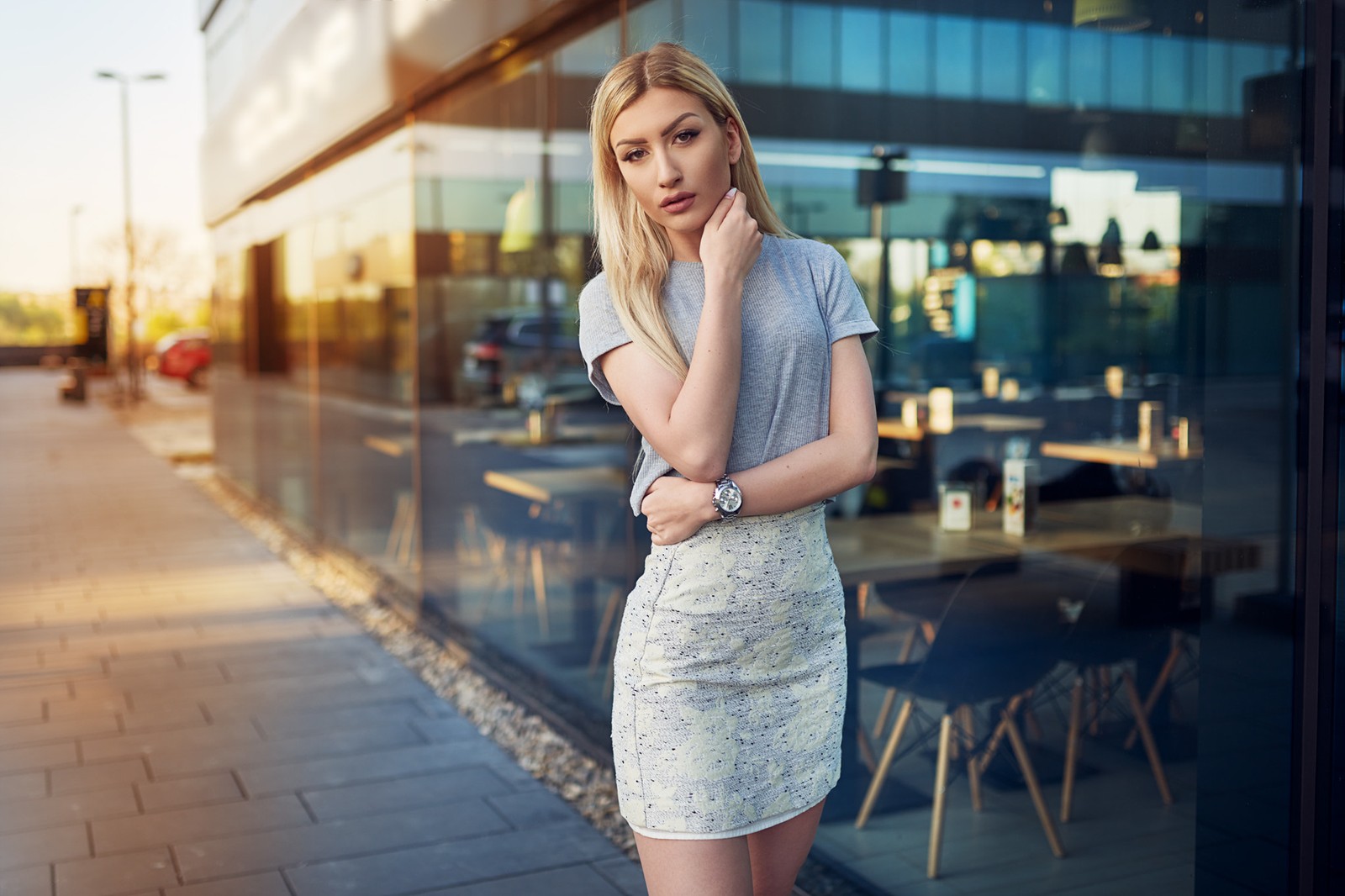 Une femme blonde en robe courte se tenant devant un restaurant (beauté, portrait, vêtements, épaule, mode de rue)