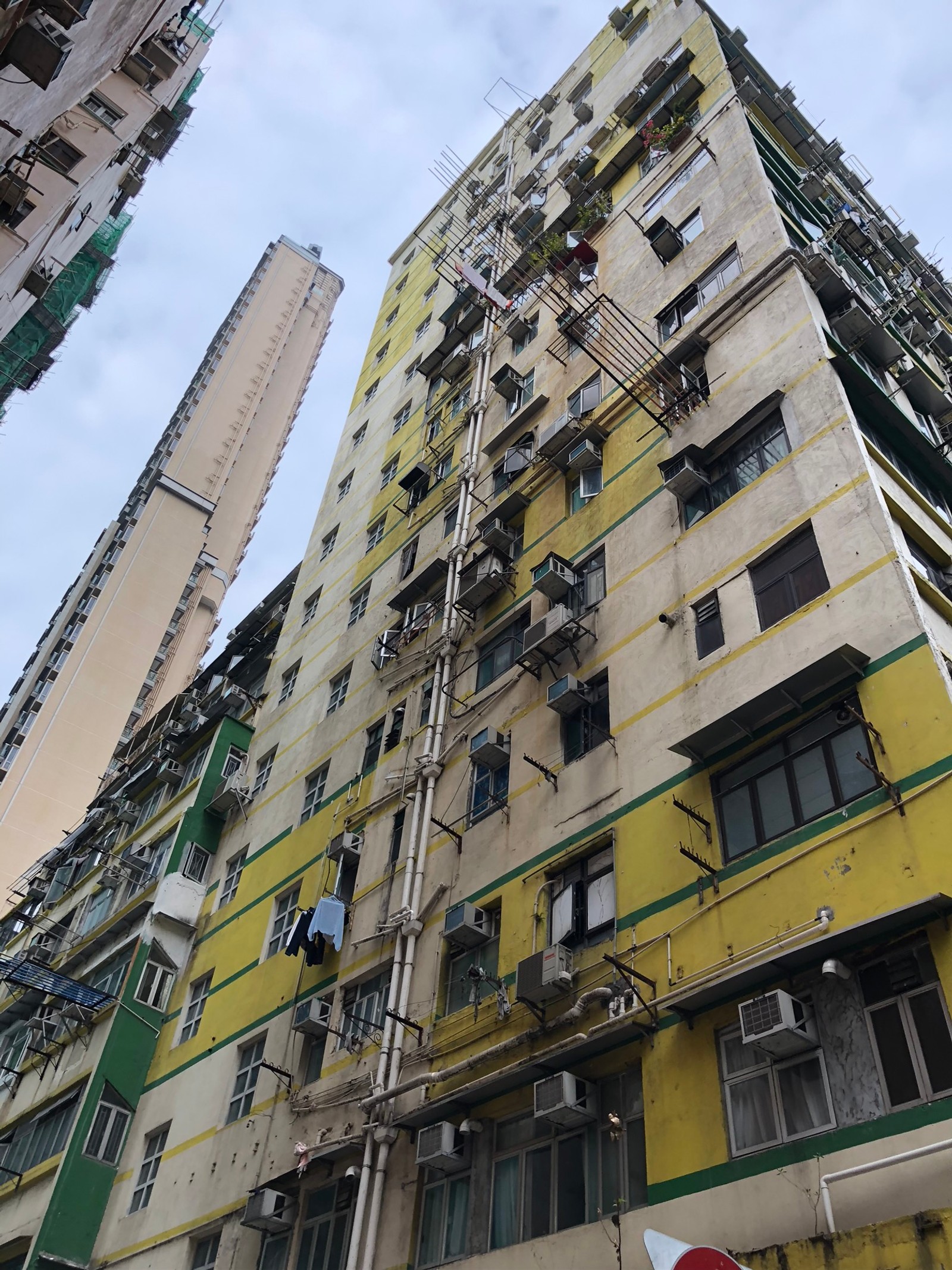 Um prédio abandonado com muitas janelas e uma placa de pare vermelha (bloco de torre, dia, arquitetura, amarelo, condomínio)