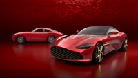 Aston Martin DBS GT Zagato in Supernova Rot mit klassischem Aston Martin Modell vor einem kräftigen roten Hintergrund.