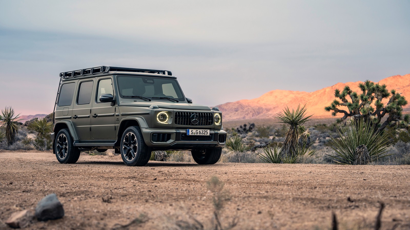 Ein grüner jeep parkt in der wüste mit bergen im hintergrund (mercedes amg g 63, 2024, mercedes amg g klasse suv, mercedes amg g class suv, g wagon)