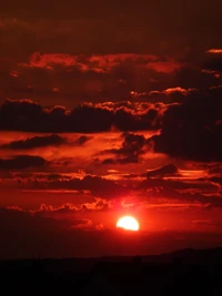 Lebendiger roter Sonnenuntergang, der einen bewölkten Horizont erleuchtet