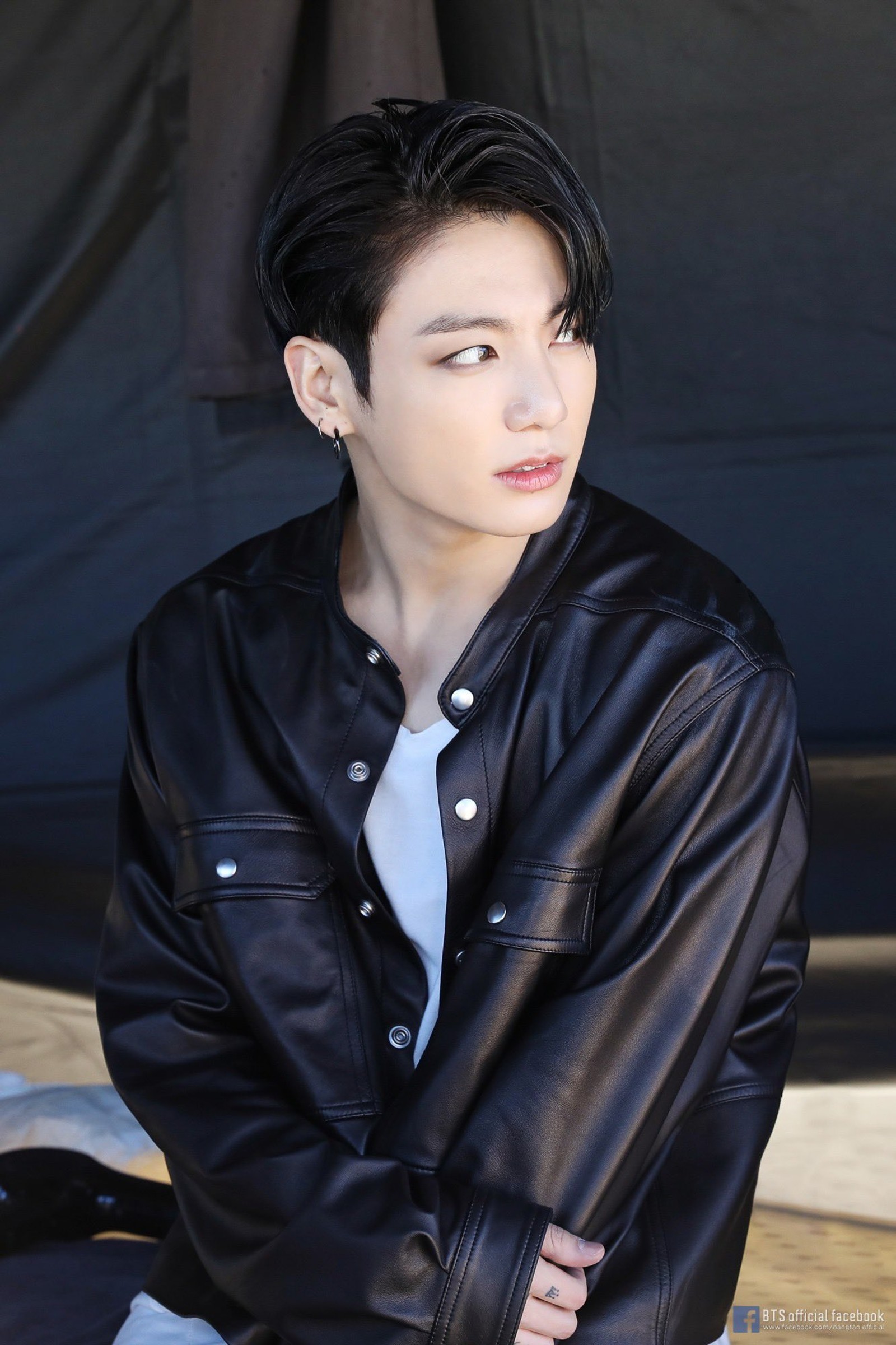 Arafed man in a black jacket sitting on a bench (bts, bts on, jungkook)