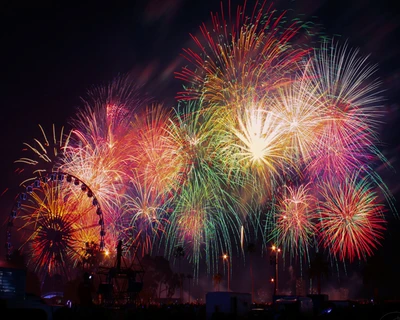 Un spectacle vibrant de feux d'artifice colorés illuminant le ciel nocturne, avec une grande roue visible au premier plan.