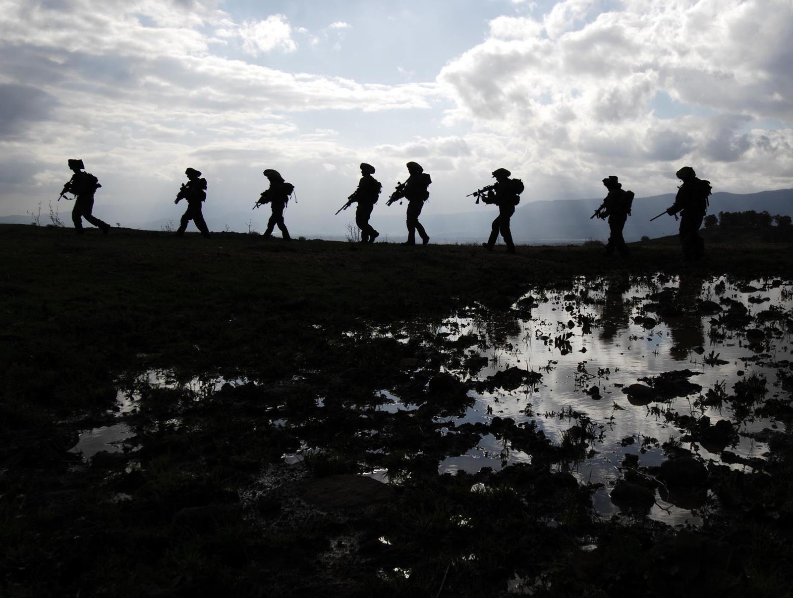 Des soldats marchent à travers un champ de boue avec leurs armes (bataille, combat, arme, militaire, soldat)