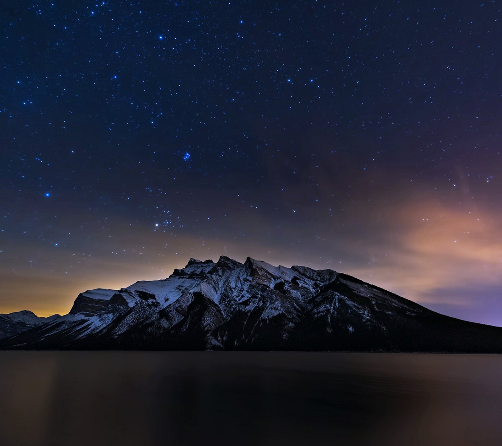 Una vista de una montaña con un lago y un cielo lleno de estrellas (alberta, canadá, montañas, noche, estrellas)