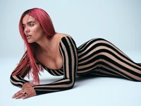 Karol G in a striking striped bodysuit, showcasing elegance and confidence.