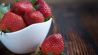 Fraises fraîches dans un bol blanc sur une surface en bois