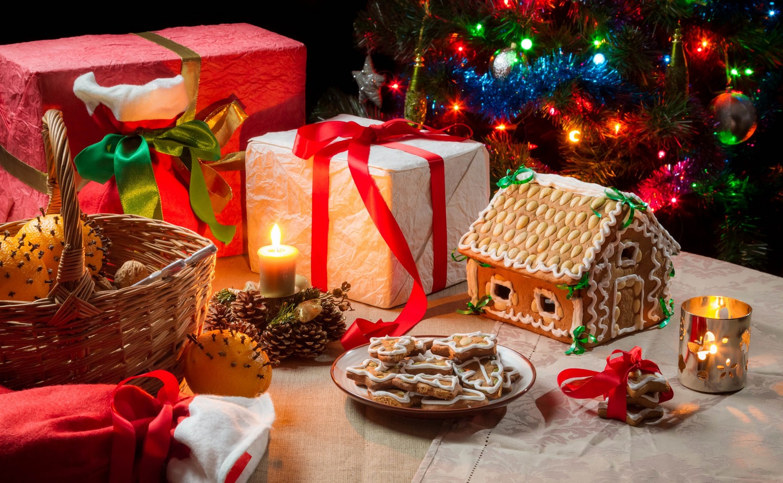 A close up of a table with a plate of cookies and a christmas tree (gingerbread house, gingerbread, gingerbread man, christmas cookie, food)