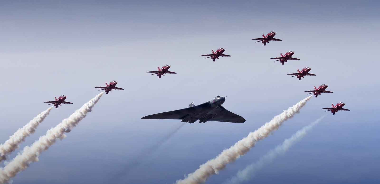 Arafed jet flying in formation with red and white smoke trailing behind it (avro vulcan, airplane, air show, aircraft, air force)