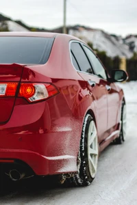 Sedã esportivo vermelho com rodas de liga leve em uma estrada nevada