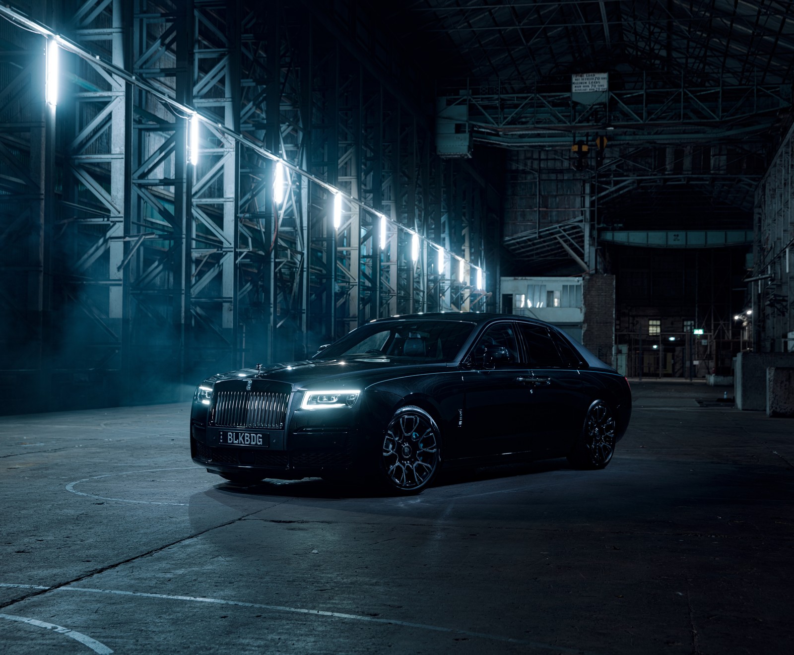 Eine nahaufnahme eines schwarzen autos, das in einem dunklen lagerhaus geparkt ist (rolls royce black badge ghost, 8k, 2022, nacht, 5k)