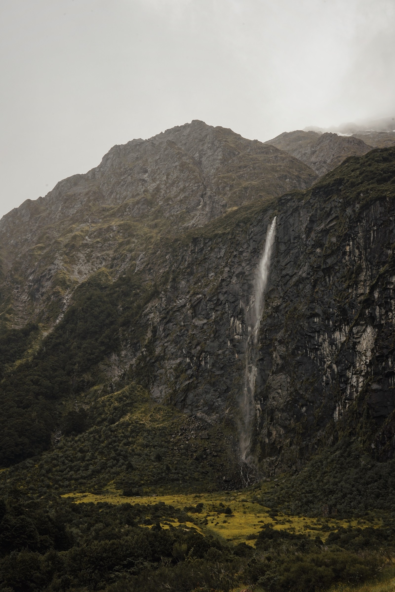 Une cascade sort d'une montagne sous un ciel nuageux (la cascade, falaise, hauts plateaux, formes montagneuses, eau)