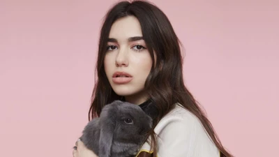 Dua Lipa con un conejo contra un suave fondo rosa.