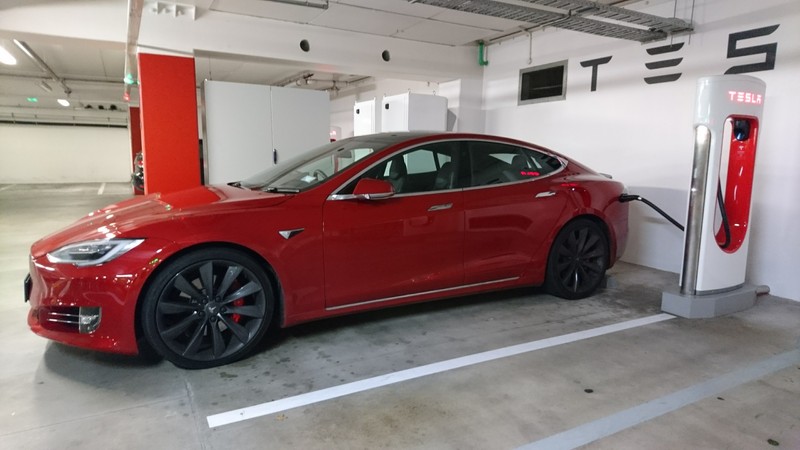 Красный tesla model s припаркован на парковке с зарядной станцией (тесла модель 3, tesla model 3, tesla model s, тесла, тесла родстер)