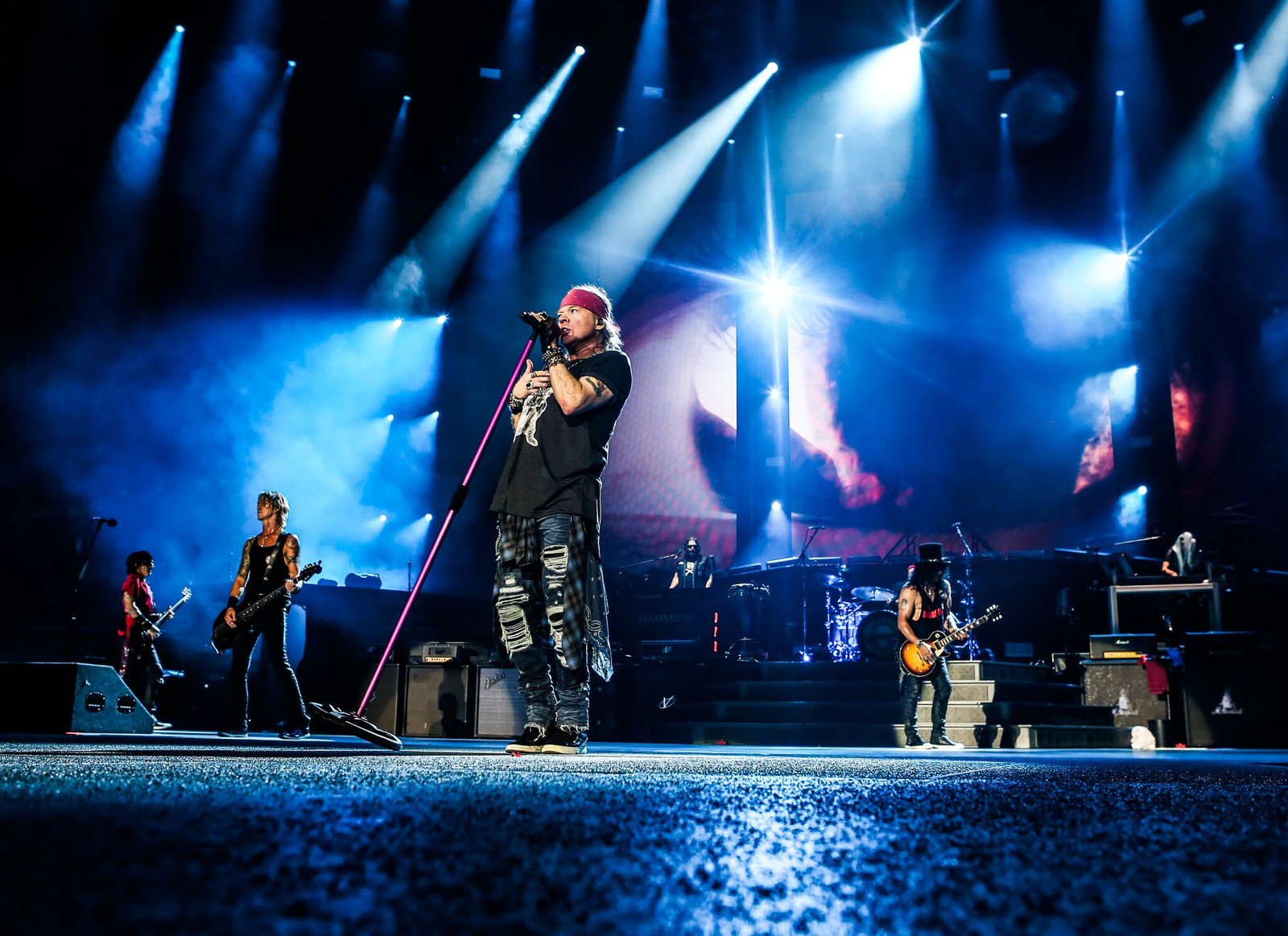 A man standing on a stage holding a microphone and singing (stage, rock concert, not in this lifetime tour, guns n roses, concert)