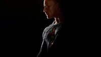 Dwayne Johnson en tant que Black Adam, illuminé contre un fond sombre, montrant la silhouette puissante du personnage.