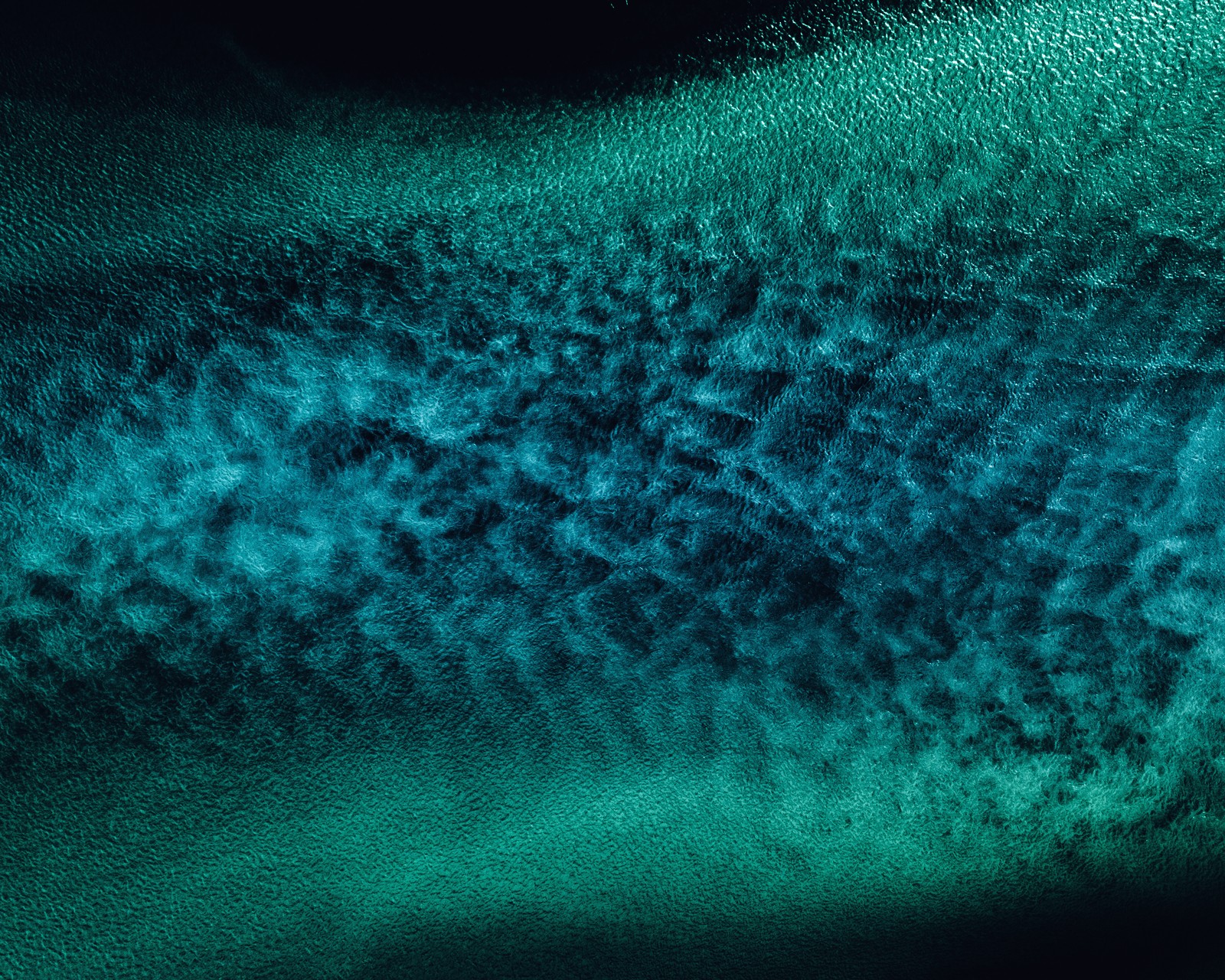 Una vista aérea de un barco en el océano con un cielo azul (océano, corriente de agua, vista aérea, azul, verde azulado)