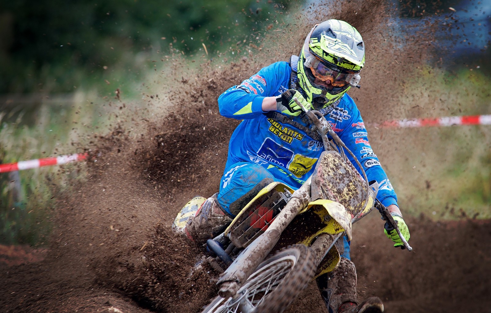 Um piloto de motocross árabe em azul e amarelo passando por uma área lamacenta (motocross, motocicleta, corridas, motocross estilo livre, solo)