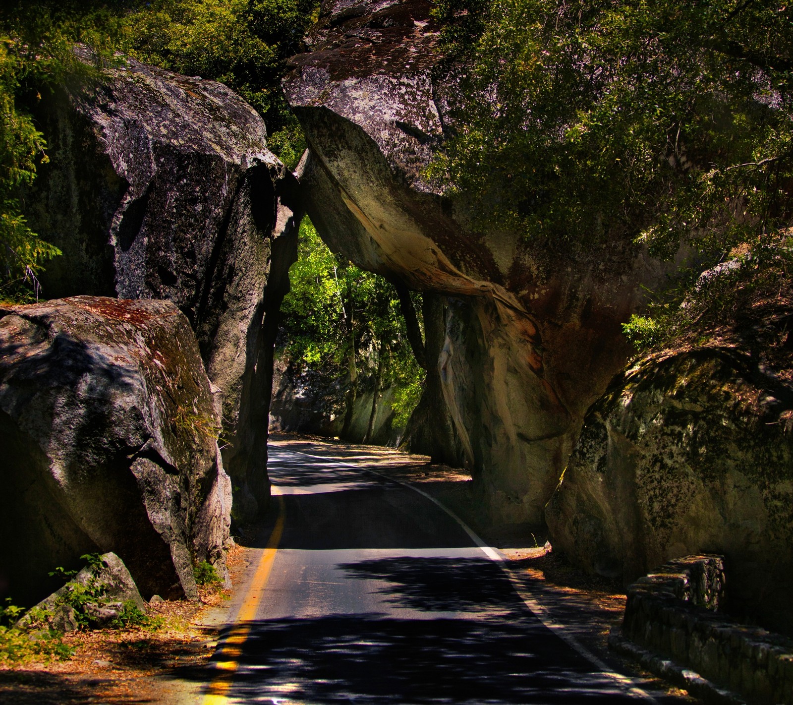 Il y a une grande formation rocheuse sur le bord de la route (chemin, route, roche, pierre, tunnel)