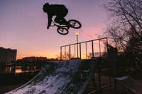 Piloto de BMX freestyle voando ao crepúsculo