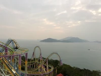 Parque de atracciones escénico con montaña rusa con vistas al mar