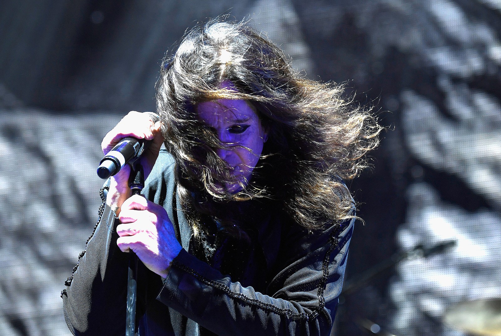 Un hombre árabe con cabello largo sostiene un micrófono y lleva una chaqueta negra. (no más giras ii, black sabbath, púrpura, desempeño, evento)