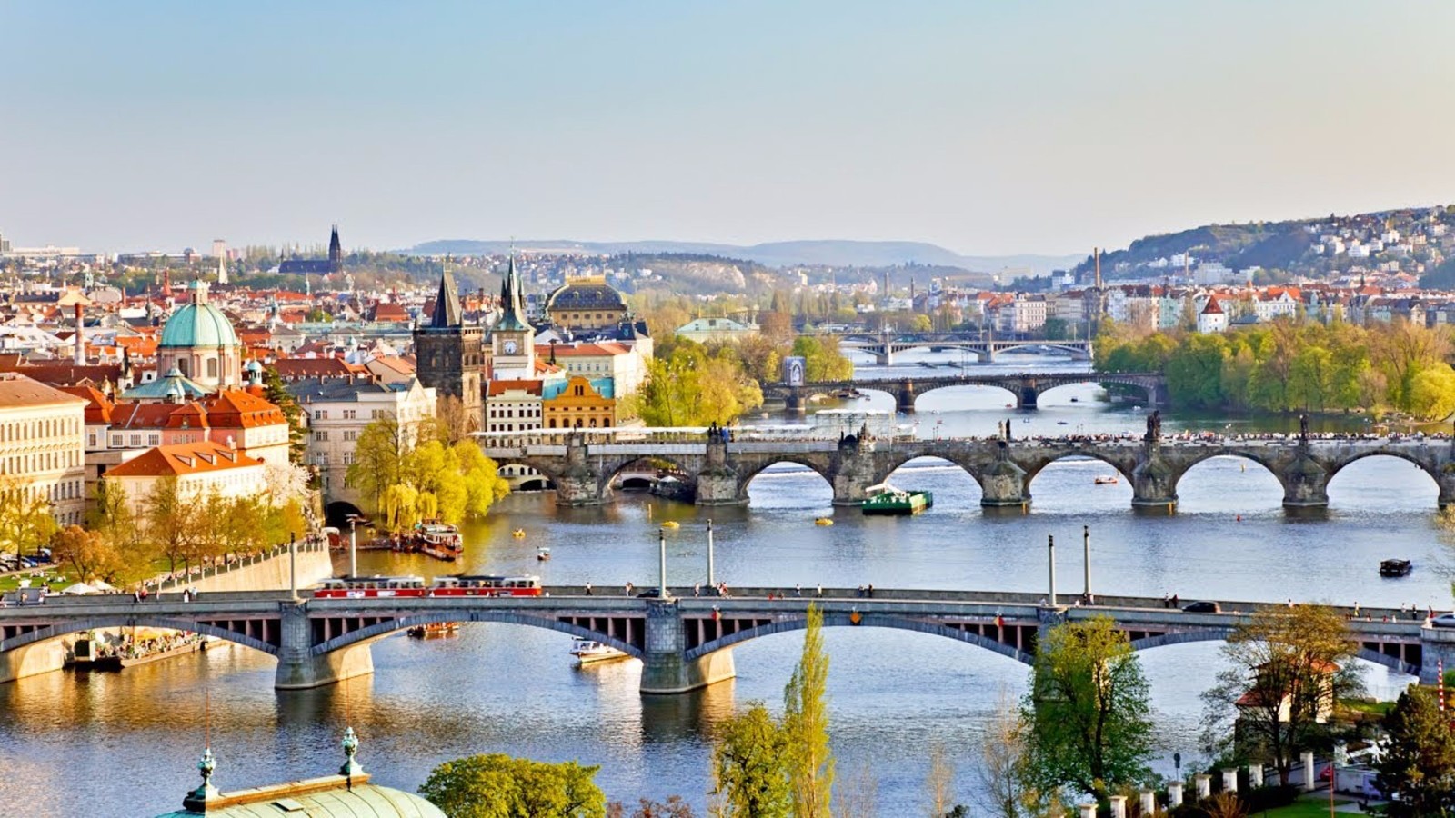 Vista aérea de uma ponte sobre um rio com uma cidade ao fundo (praga, vltava, ponte, flúmen, paisagem urbana)