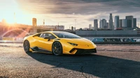 Yellow Lamborghini Huracán in an urban setting at sunset.