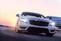 Élégante Mercedes-Benz CLS Classe blanche garée contre un fond de coucher de soleil, mettant en valeur son luxe et sa performance.