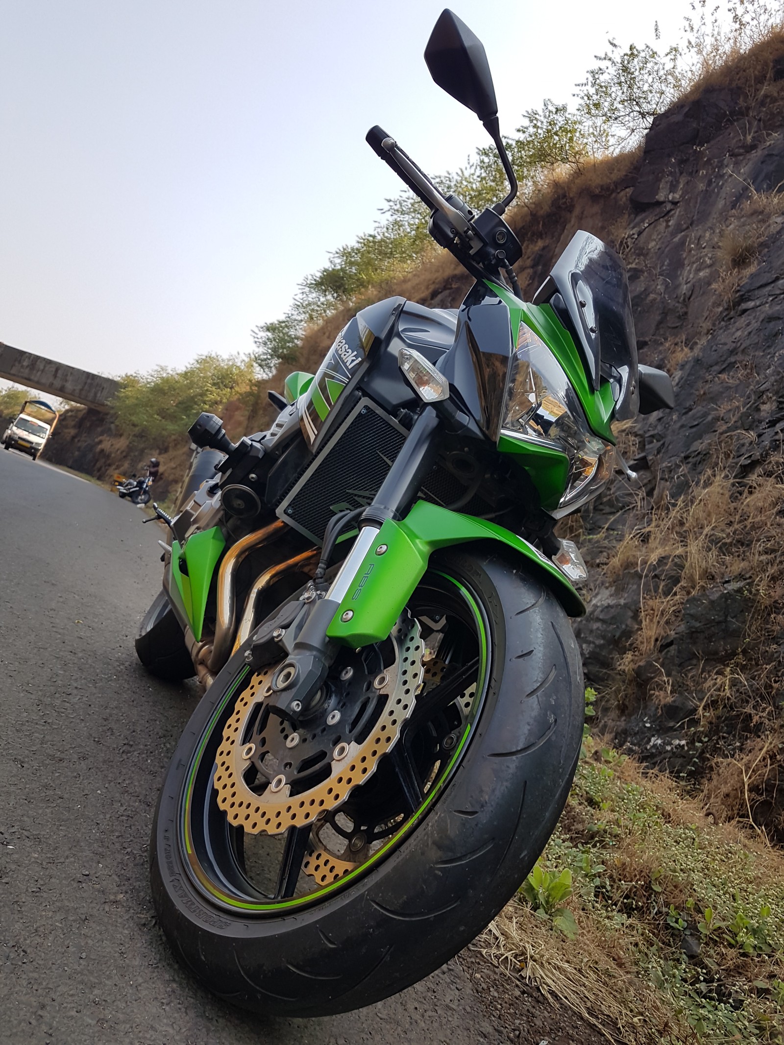 Hay una motocicleta verde estacionada al lado de la carretera (kawasaki, motocicleta)