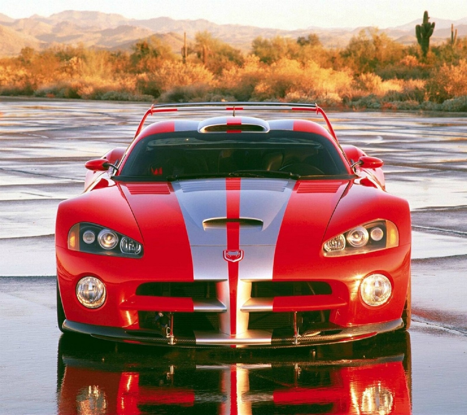 A close up of a red sports car parked on a wet surface (dodge, viper)