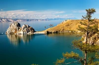 Ruhiger See mit Landschaft, die majestätische Berge und Uferbäume spiegelt