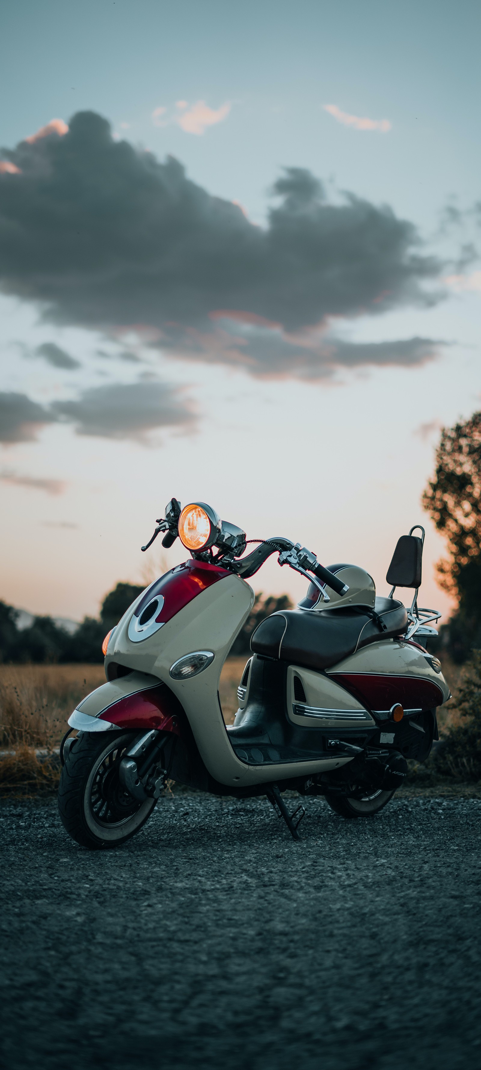 Hay una motocicleta estacionada al lado de la carretera (coches, agua, neumático, rueda, nube)