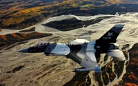 F-16 Aggressor Aircraft Soaring Over a River Landscape