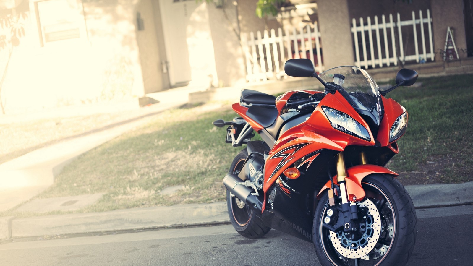 Hay una motocicleta roja estacionada al lado de la calle (yamaha motor company, motocicleta, coche, neumático de automóvil, iluminación automotriz)